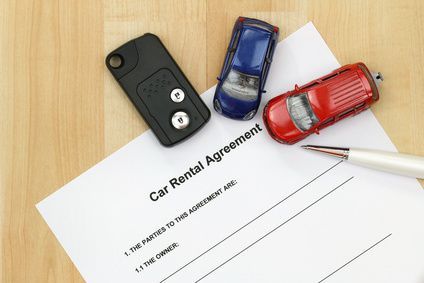 off site or on site - Closeup of car rental agreement paper next to a remote car key, a pen and mini car models